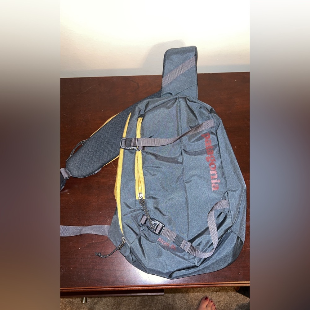 Patagonia sling bag with a dark gray body and mustard accents